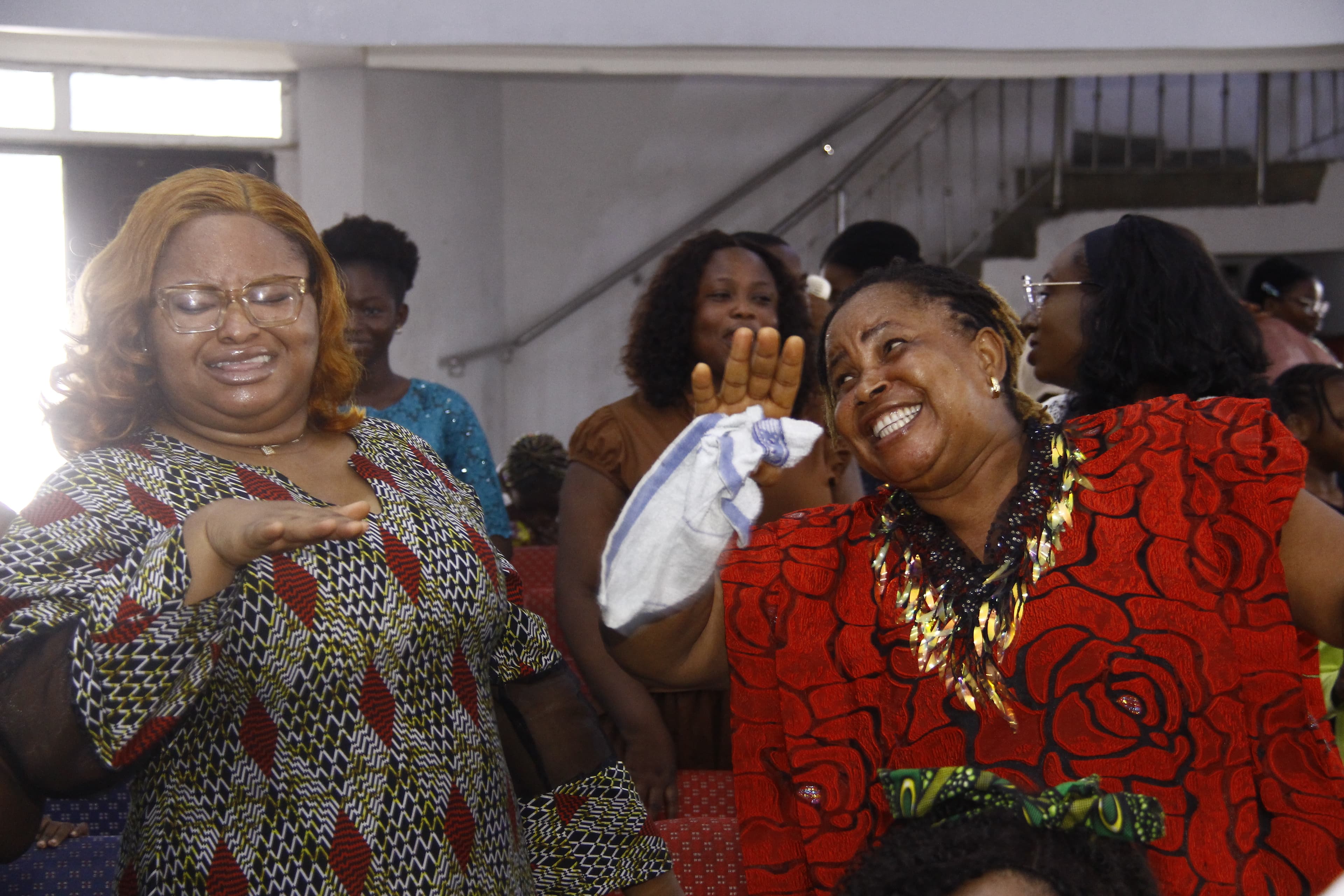 Two women laughing and clapping in colorful African prints