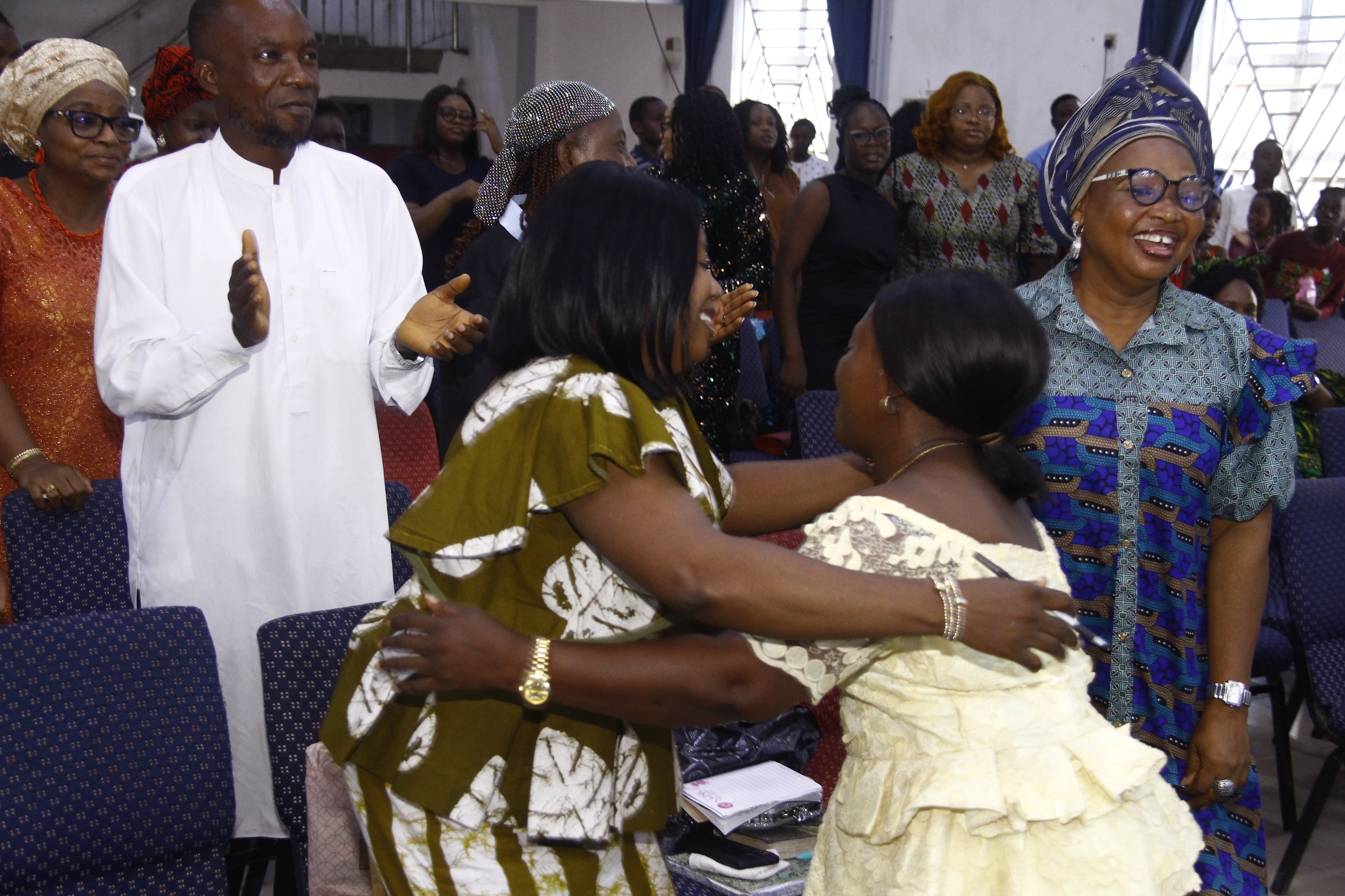 Women hugging in the aisle with joyful smiles