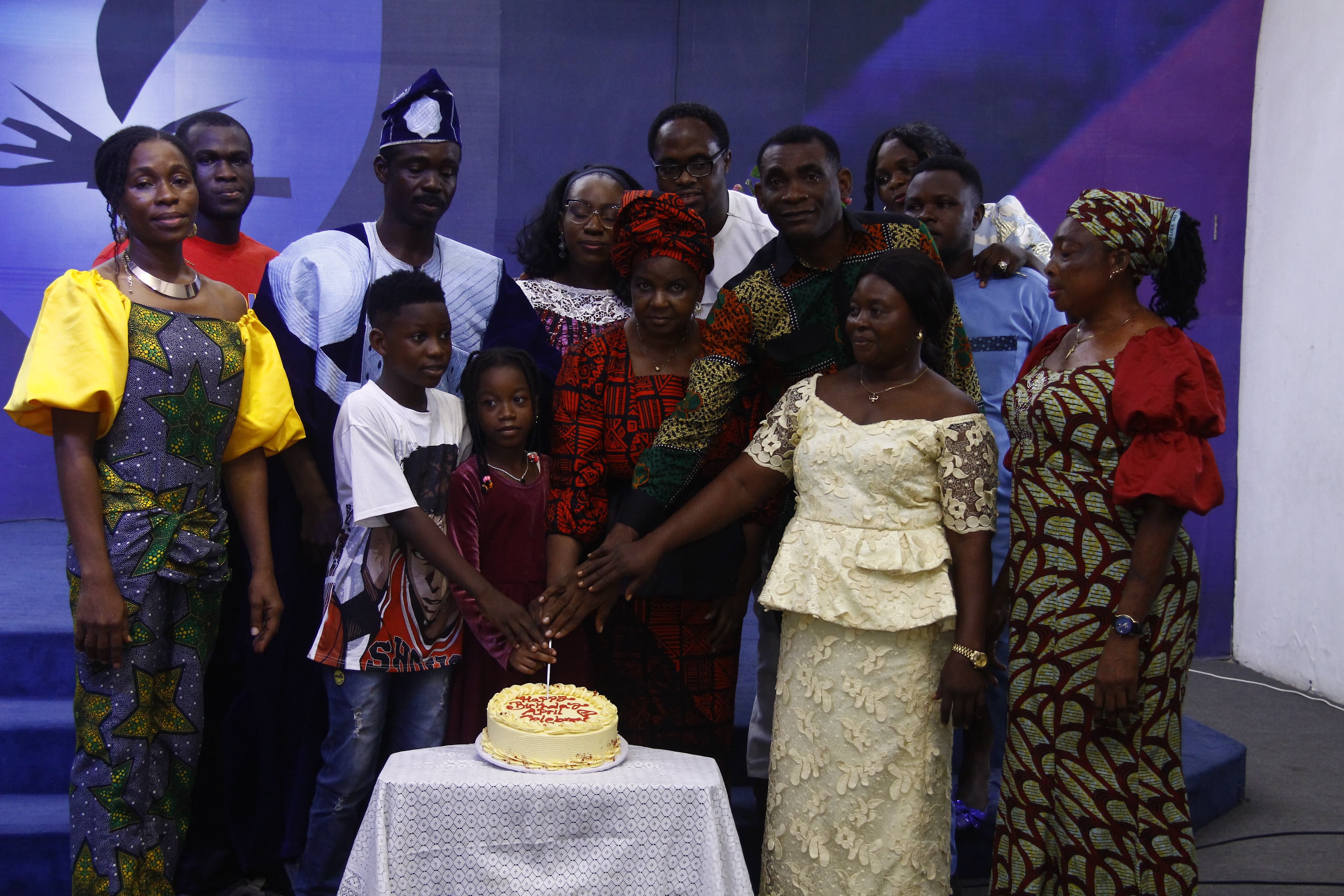 Family posing with cake in vibrant African attire