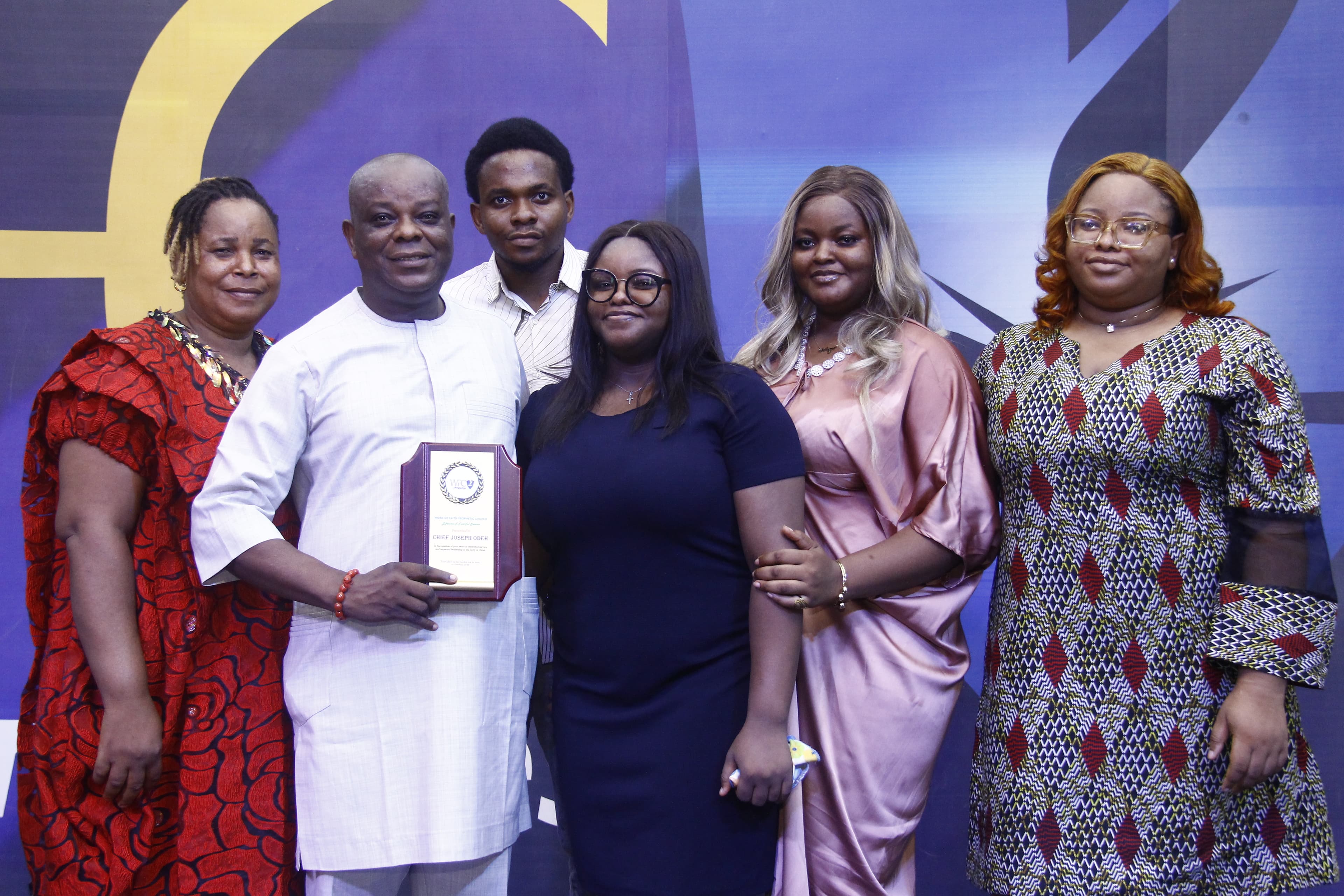 Family receiving award on stage in colorful outfits