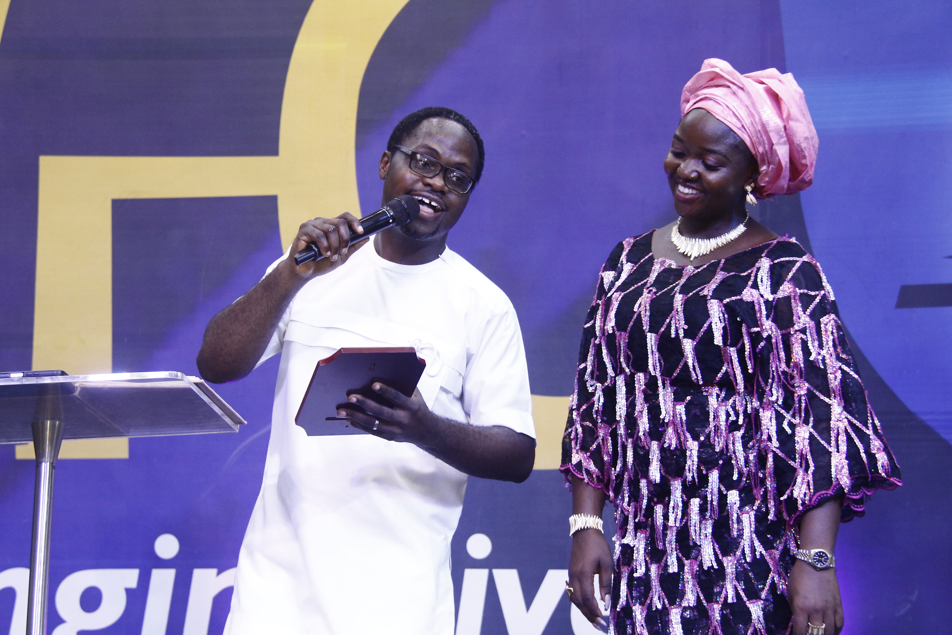 Pastor and wife on stage with award and warm smiles
