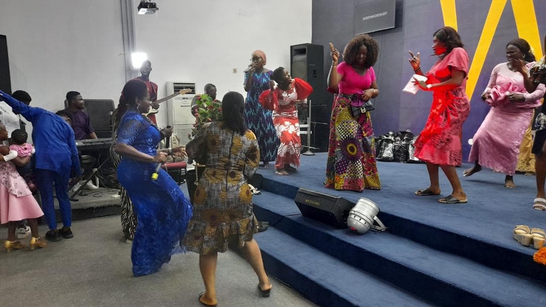 Worship leaders dancing joyfully in colorful African prints on stage