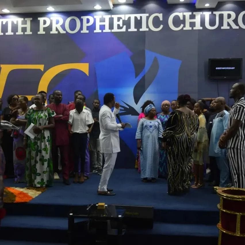 Pastor in white ministering prophetically to crowd on stage