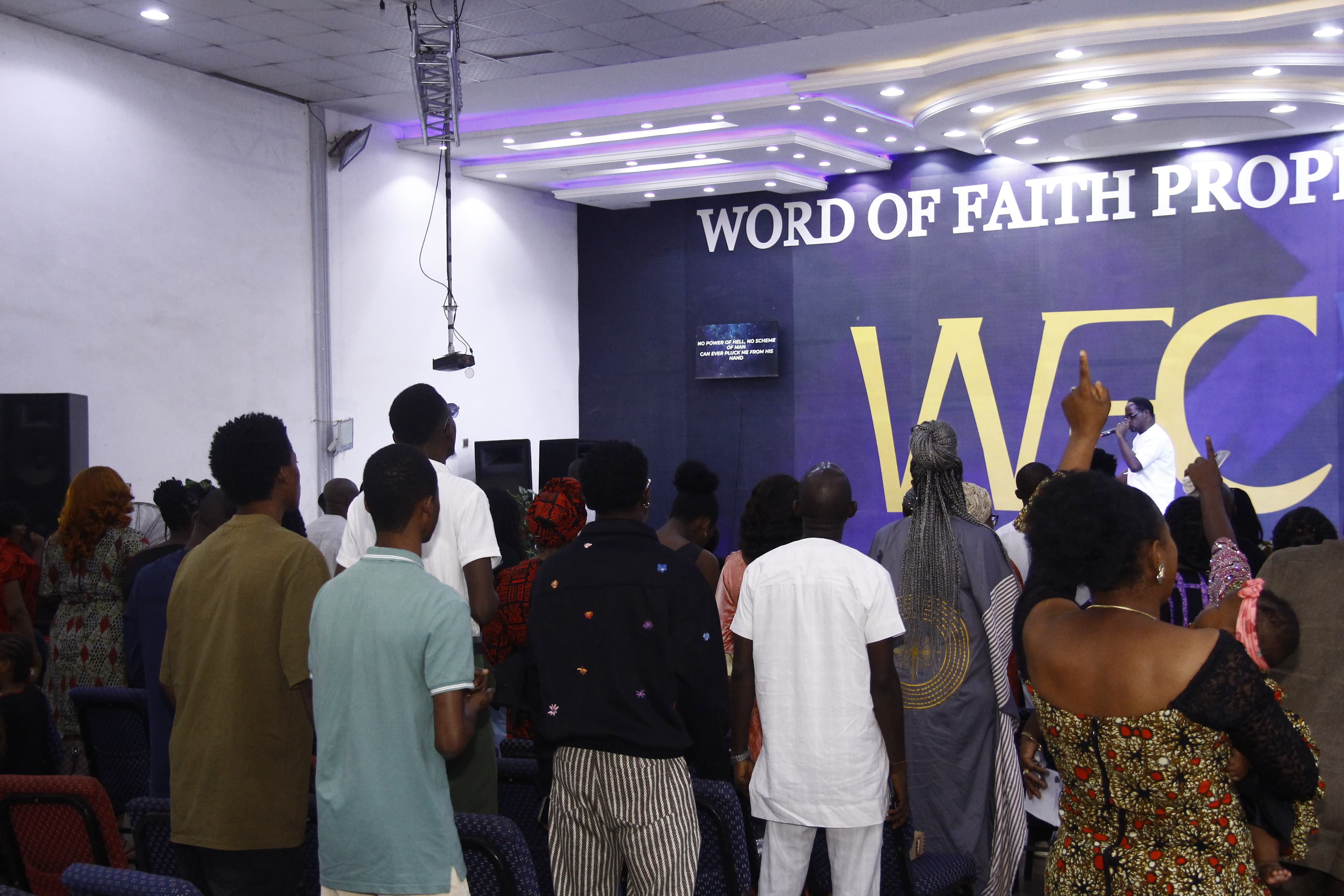 Congregation standing with hands raised facing the stage