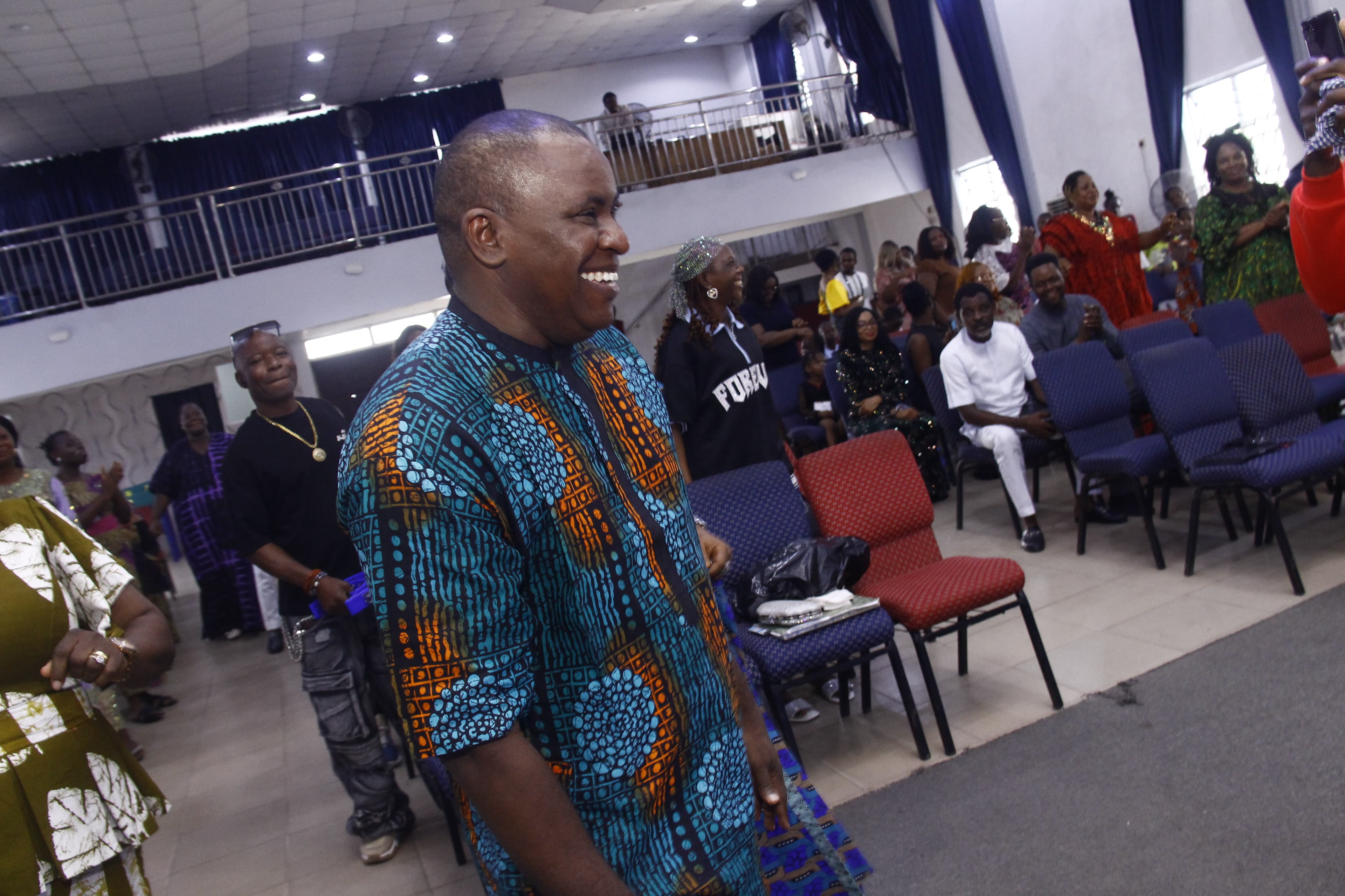 Man smiling joyfully in teal African print during service