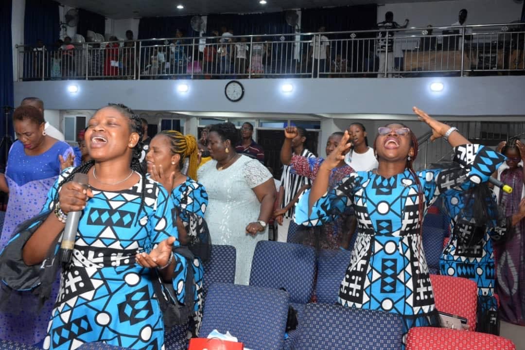 Two women in bright blue African print worshipping intensely