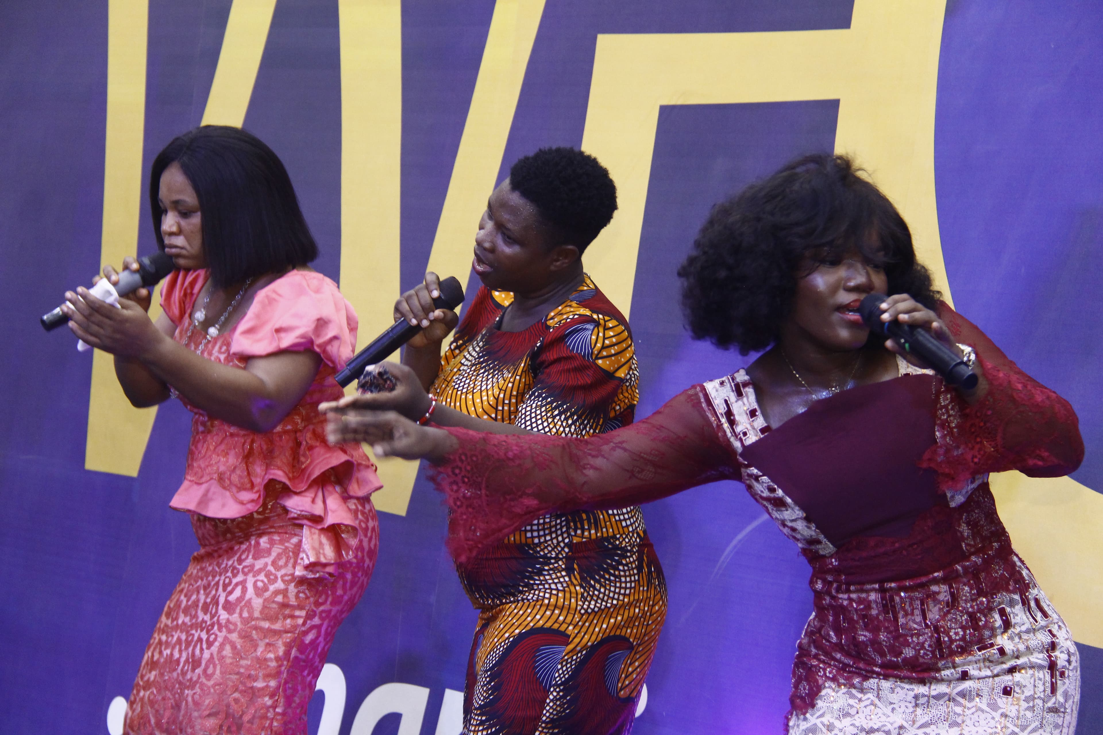 Three worship leaders on stage in colorful outfits