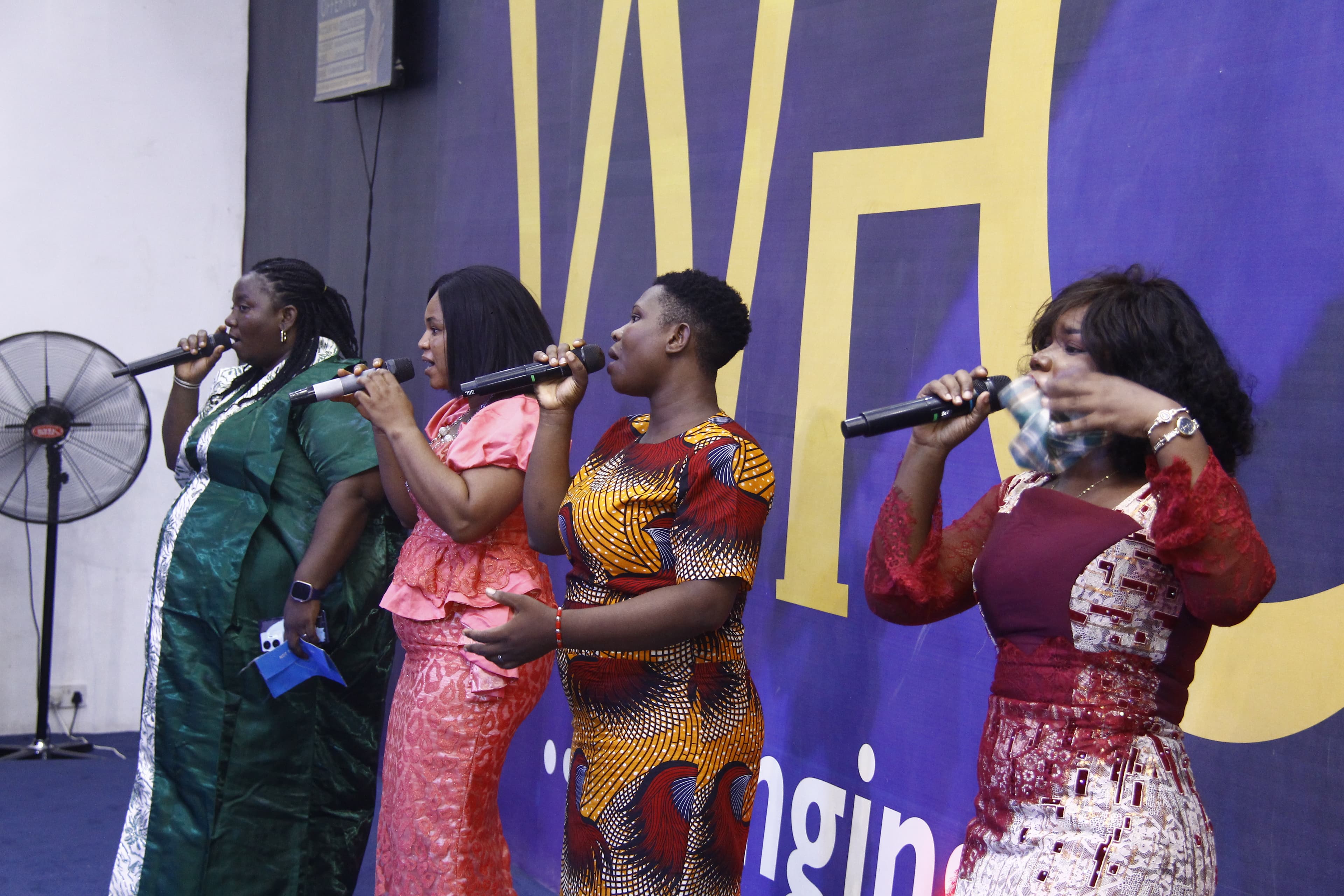 Four worship leaders singing in colorful dresses on stage